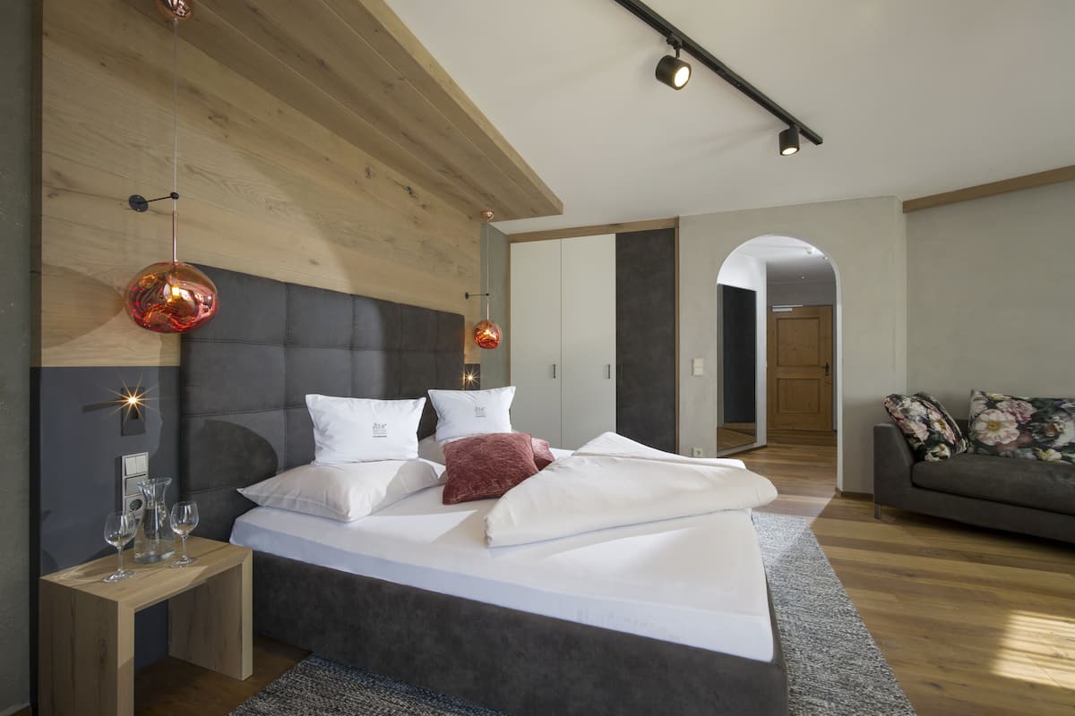 A modern bedroom with a large bed, bedside tables, and a sofa.