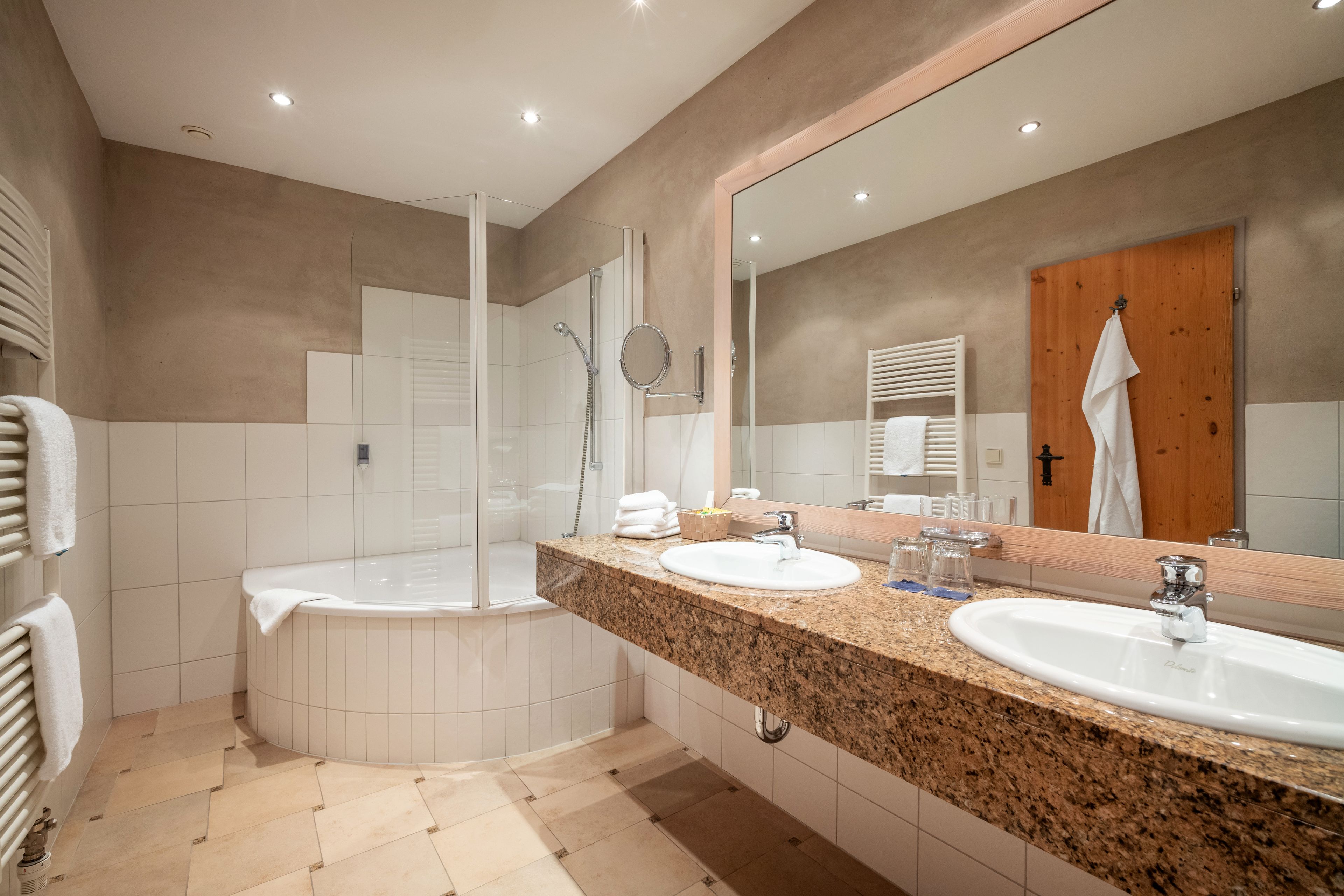 Un baño moderno con bañera, dos lavamanos, un espejo grande y una zona de ducha.