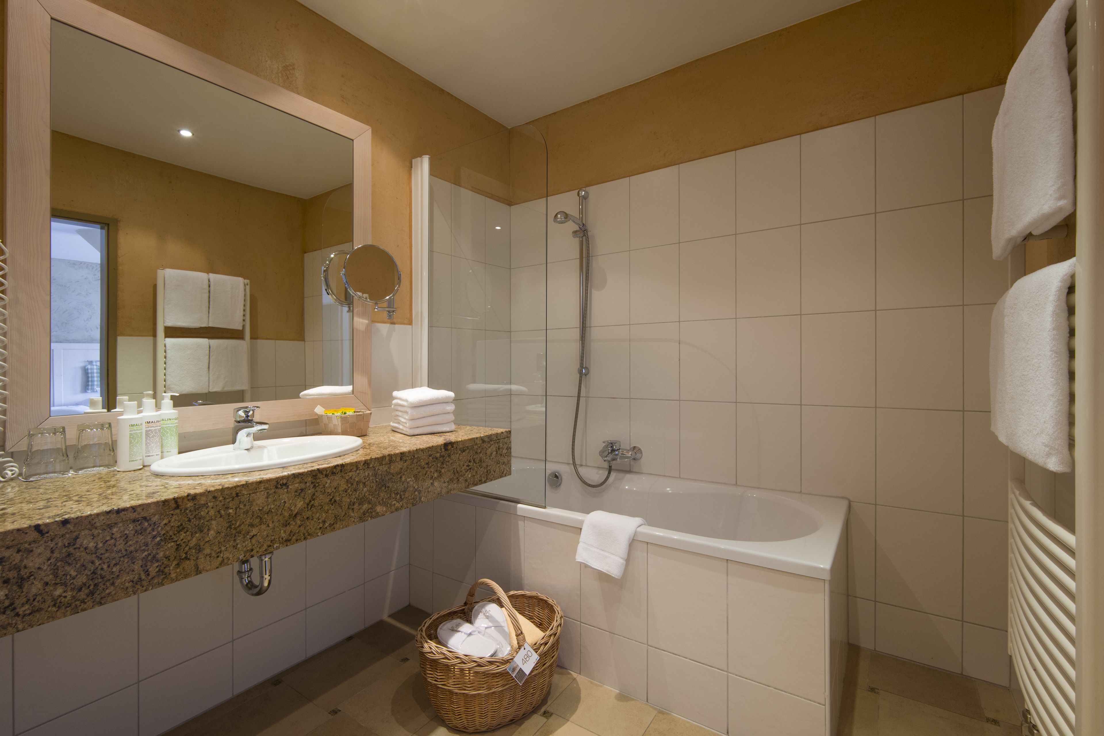 A modern bathroom with a granite countertop, a sink, a bathtub, and a shower.