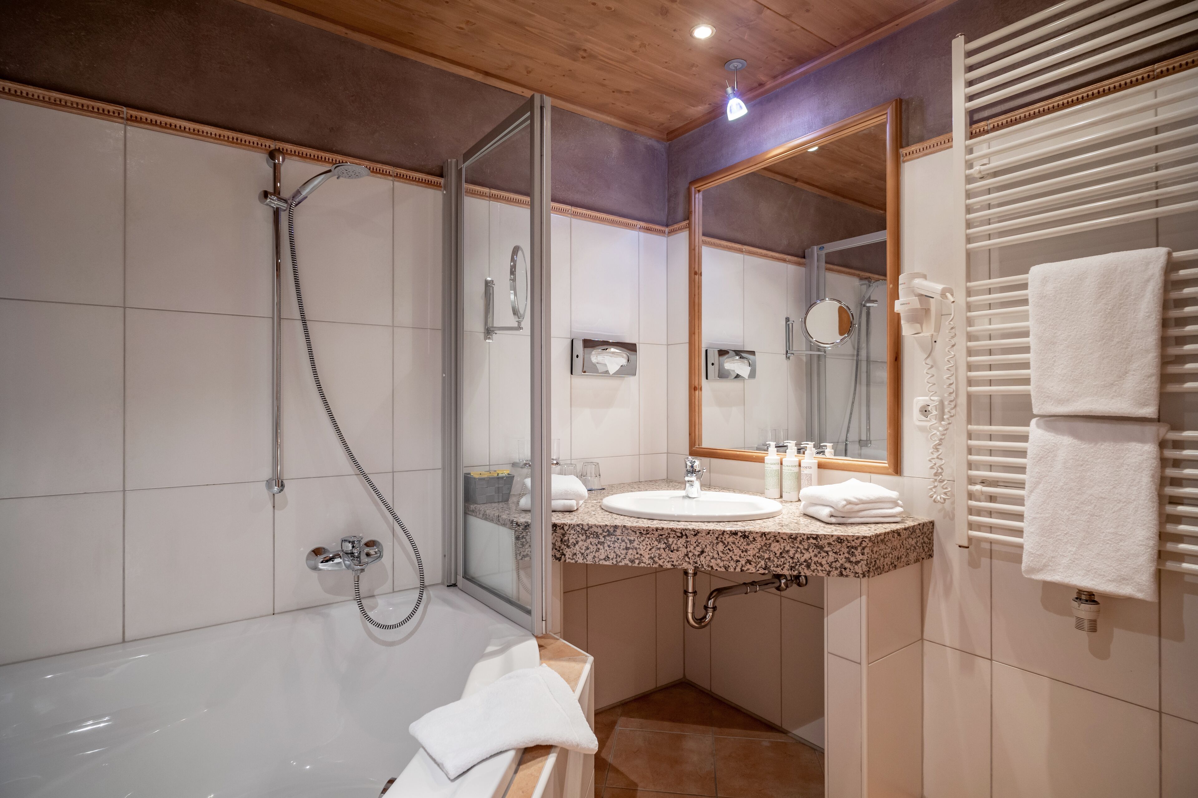 Un baño moderno con ducha de vidrio, bañera independiente y tocador con espejo.