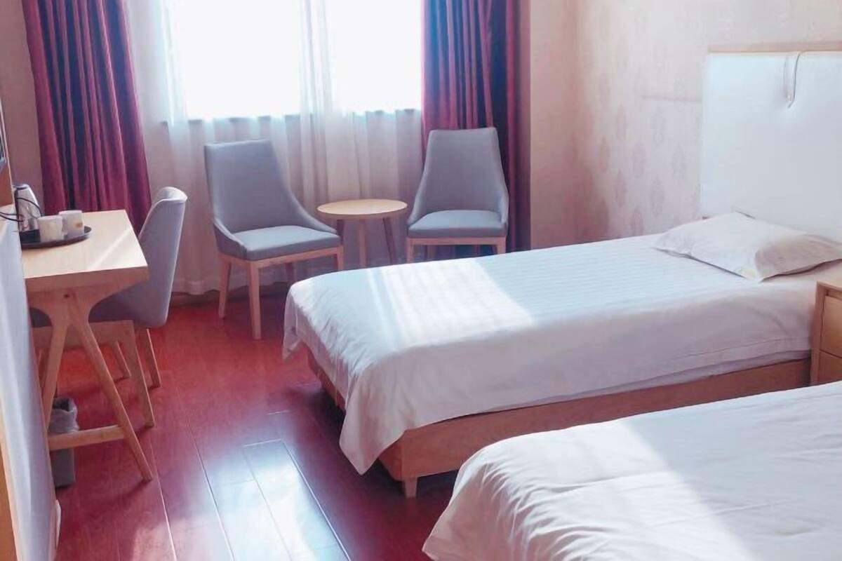 Una habitación de hotel con dos camas, un escritorio, dos sillas y una mesita redonda.