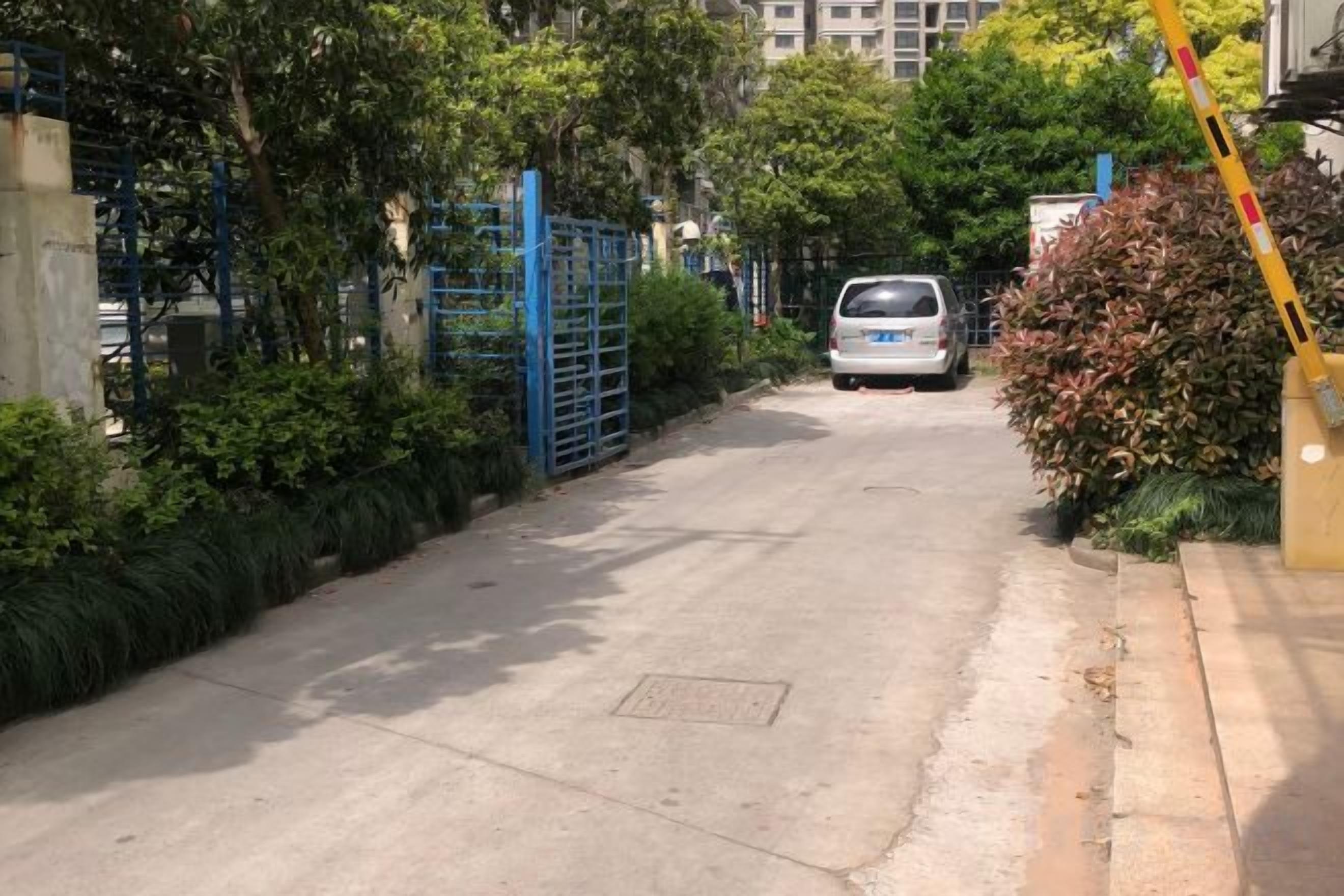 A gated driveway leading to a parked vehicle.