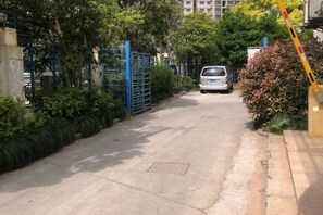 Une allée fermée par un portail menant à un véhicule stationné.
