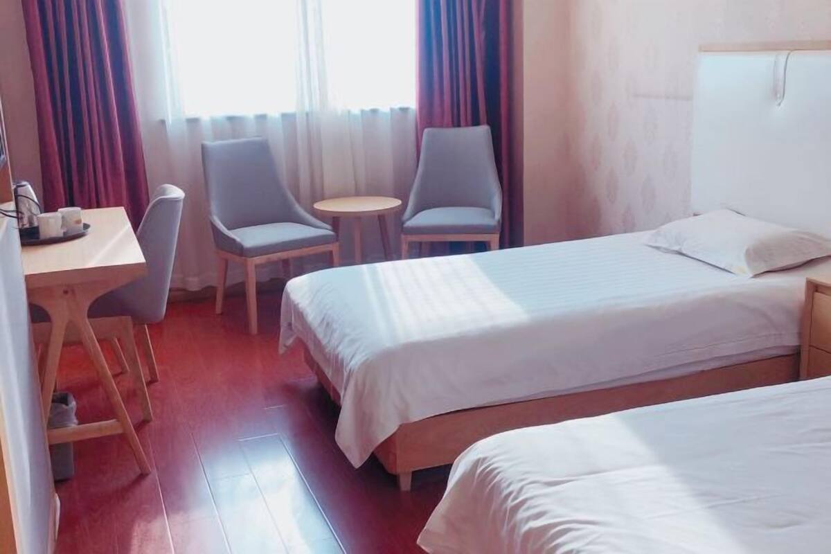 Una habitación de hotel con dos camas, un escritorio con sillas y una mesita.