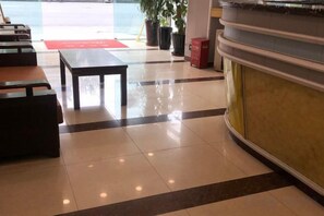 Un hall d’hôtel comprenant un comptoir d’accueil, un espace salon et une plante en pot.