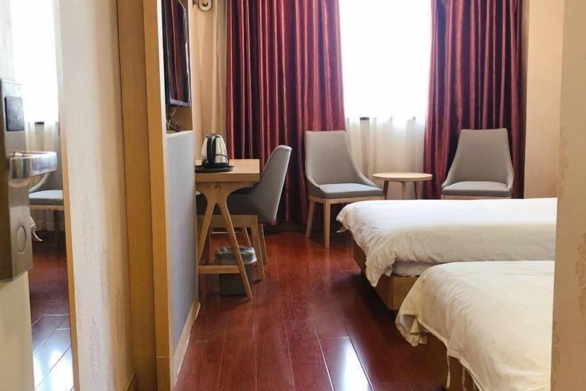 Una habitación de hotel con dos camas, un escritorio con una silla, una mesita pequeña y un televisor.