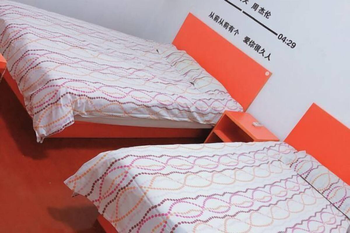 Una cama doble con ropa de cama estampada, un cabecero rojo y una mesita de noche pequeña.