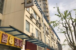 Un hôtel avec une enseigne bien visible, une échelle de secours apparente et un arbre sur le côté droit.