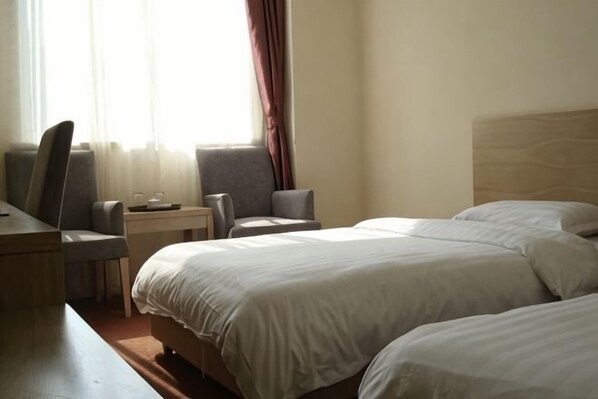 Une chambre d’hôtel avec deux lits, un bureau et une chaise.