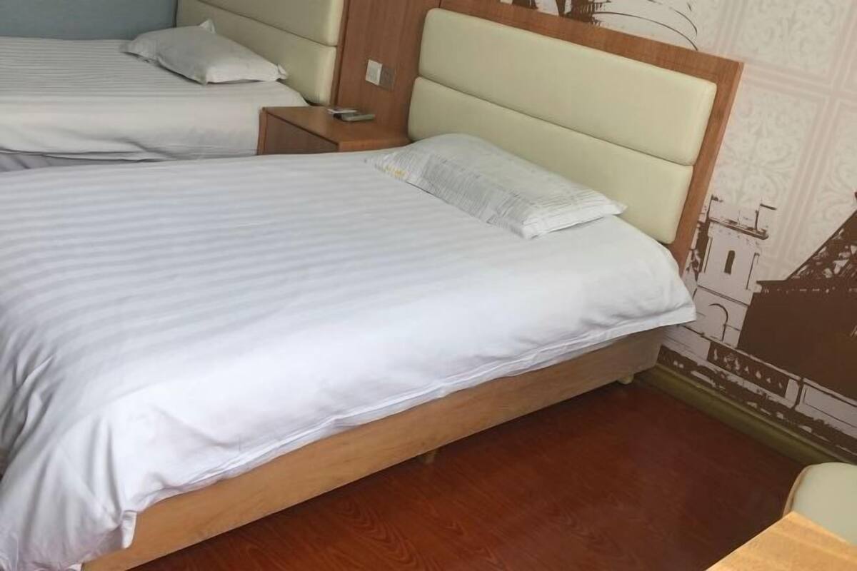 Una habitación de hotel con dos camas, cabeceros de madera y una mesita de noche.
