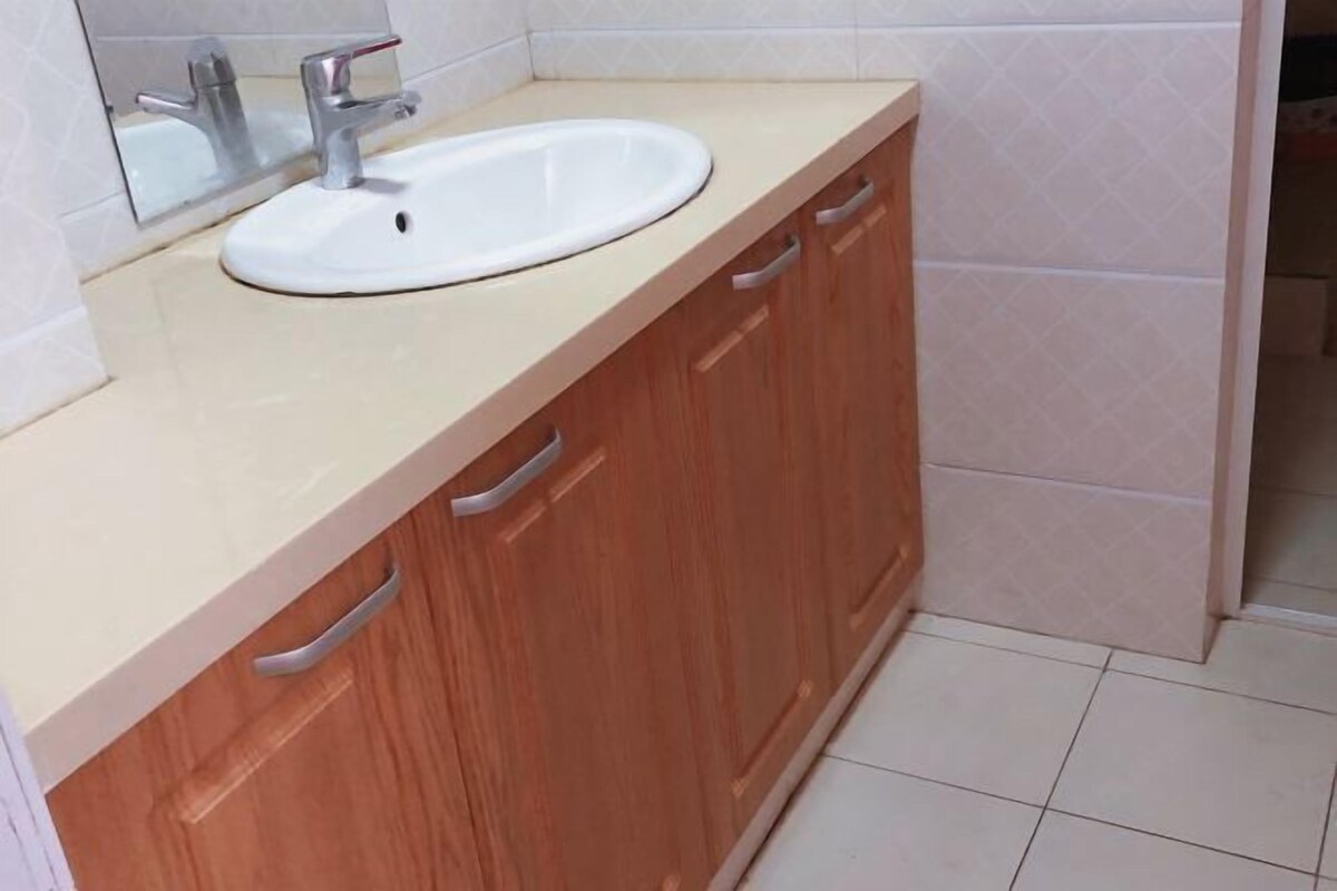 Un baño con lavamanos blanco, armarios de madera y un espejo.