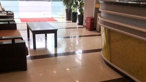 Un vestíbulo de hotel con mostrador de recepción, zona de estar y plantas en macetas.