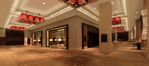 A spacious lobby with a patterned carpet, large mirrors, and red pendant lighting.