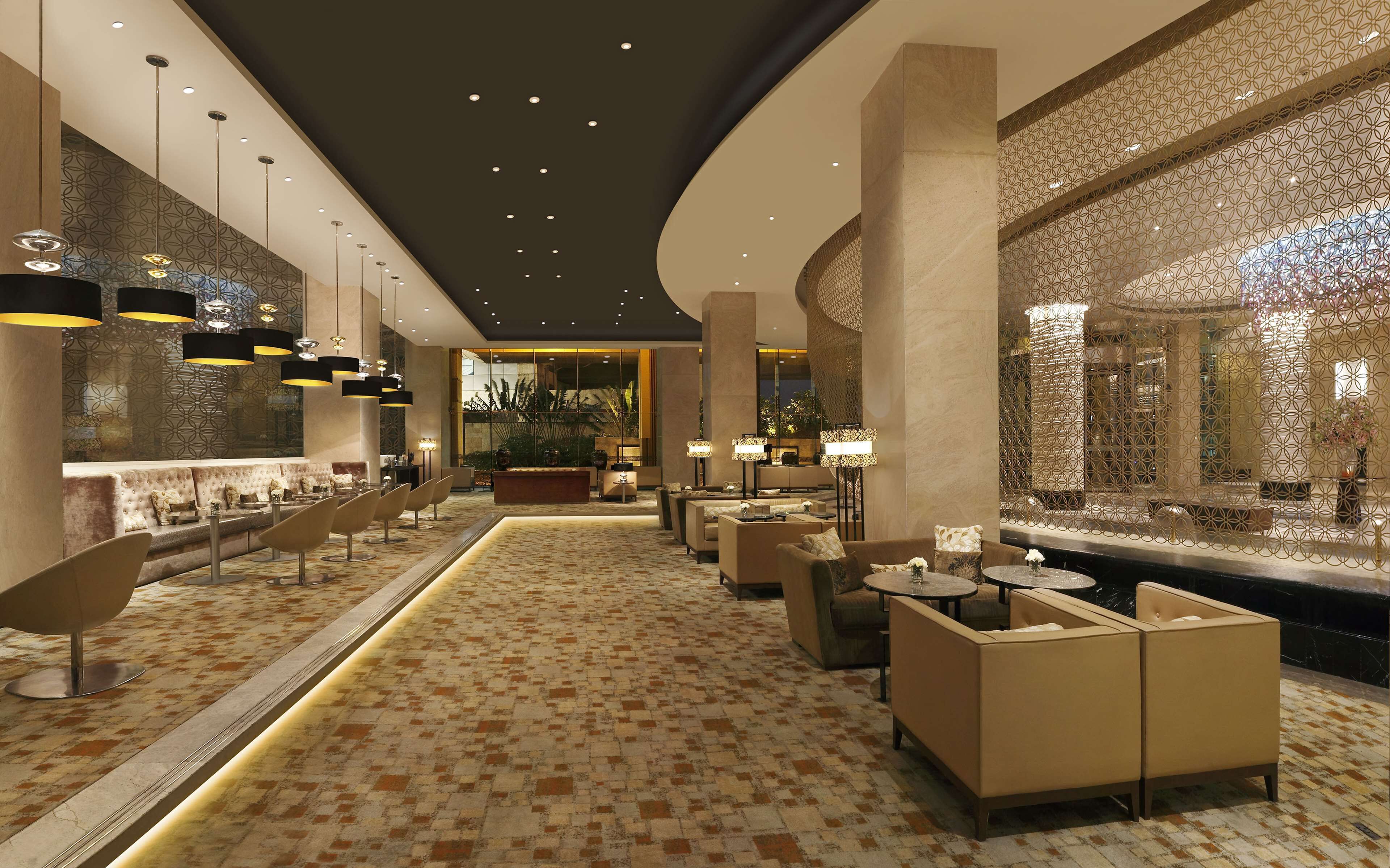 Un hall d’hôtel moderne avec un sol à motifs, des espaces de détente et un éclairage décoratif.