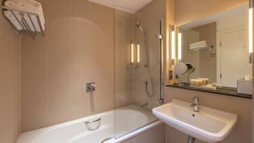 A modern bathroom with a glass-enclosed shower, a white bathtub, and a sink with a mirror above it.