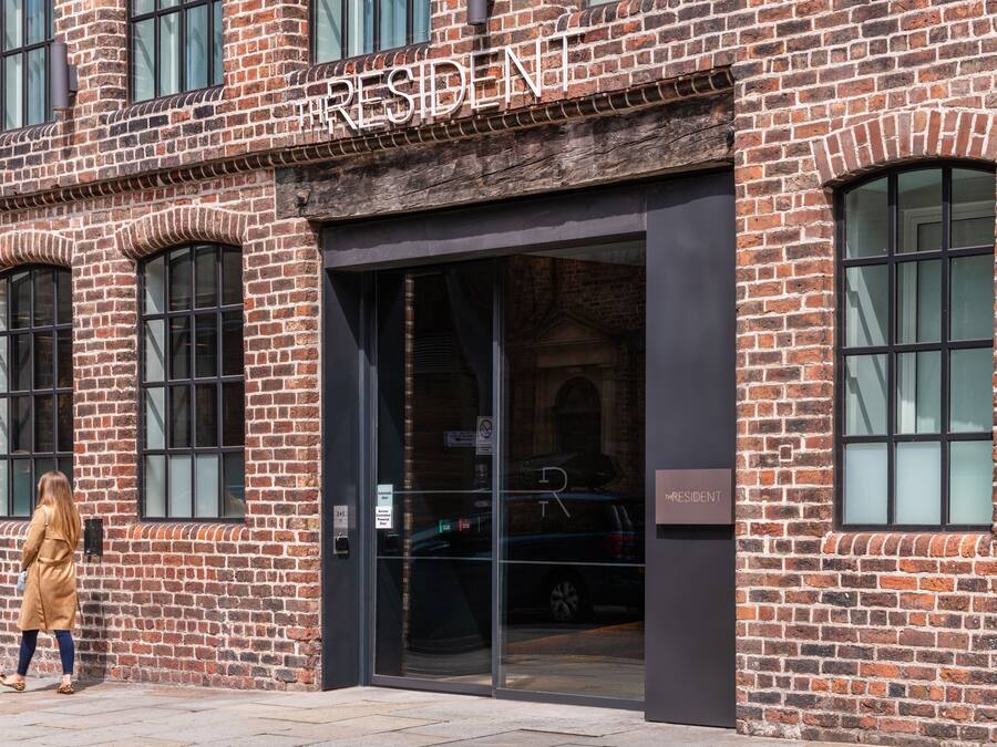 A brick building with the sign "RESIDENT" above the entrance.
