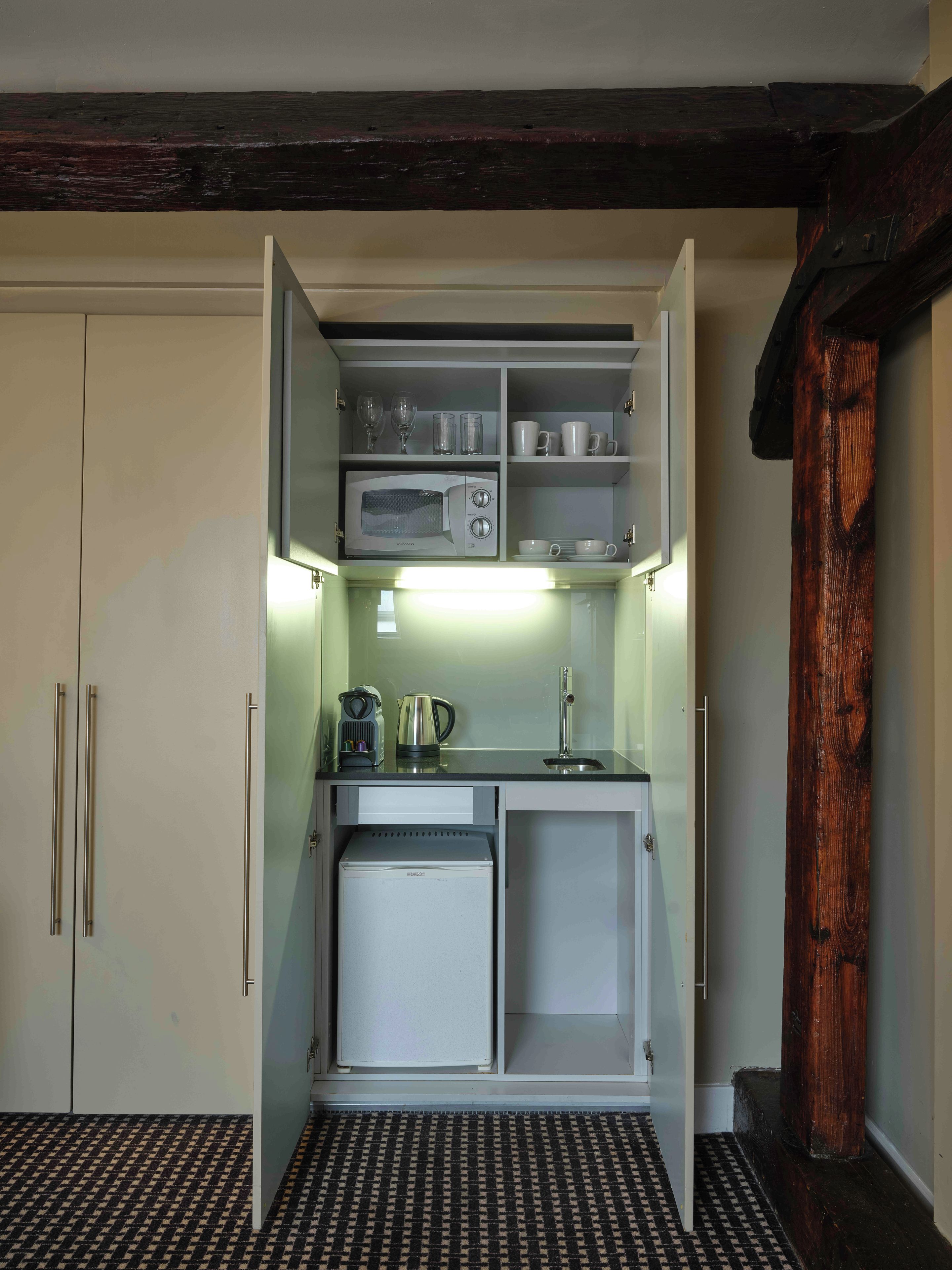A compact kitchen with a microwave, kettle, and coffee maker.