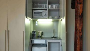 A compact kitchen with a microwave, kettle, and coffee maker.