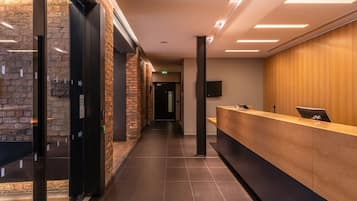 Un área de recepción moderna con un mostrador de madera, una pared de ladrillo y piso de baldosas.