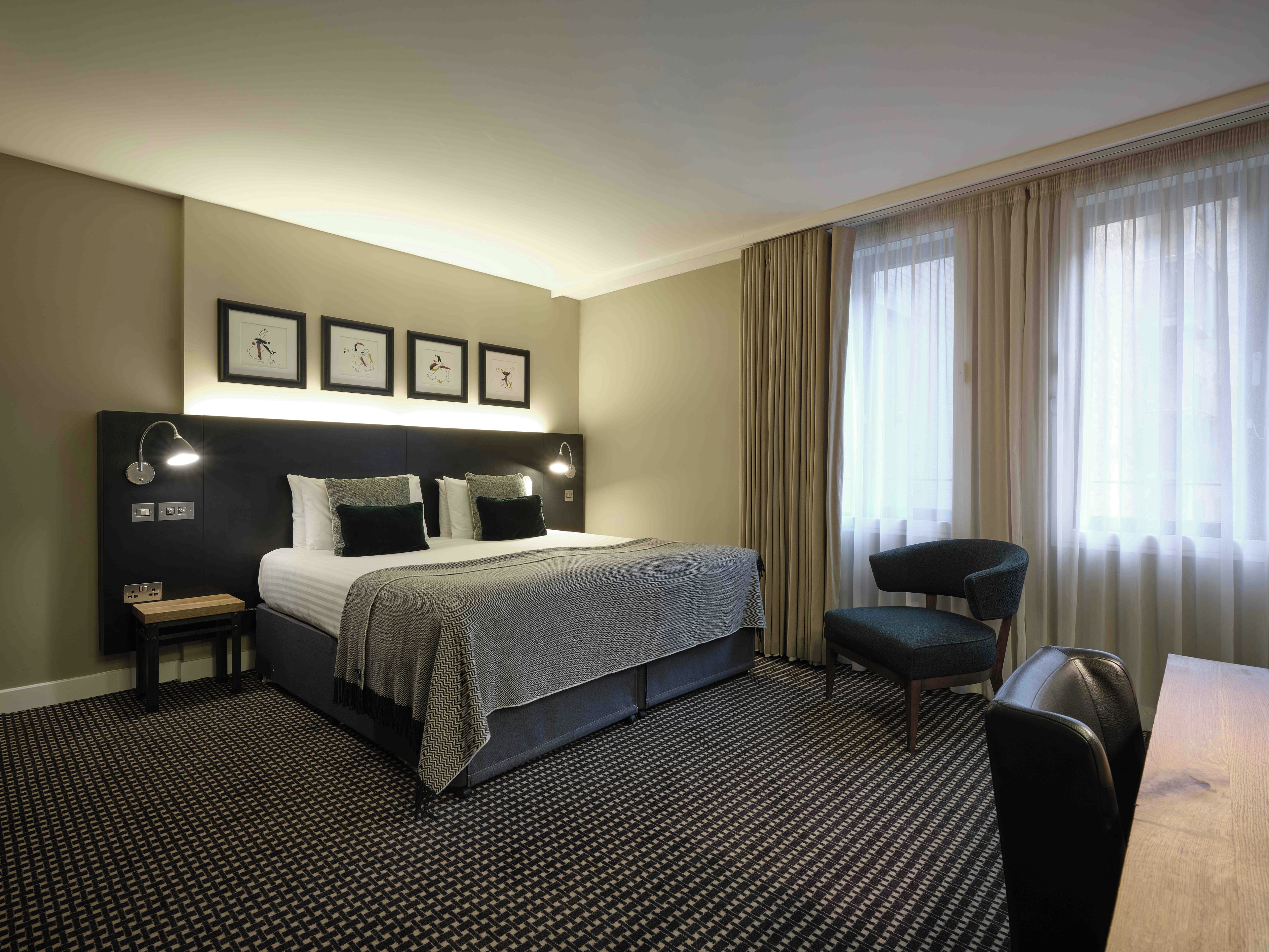 A hotel room with a bed, bedside tables, a desk, and a chair.