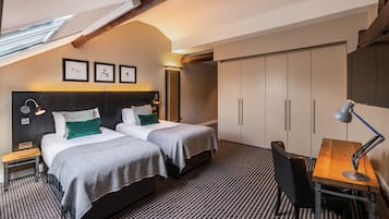 Habitación de hotel con dos camas, un escritorio y un armario grande.