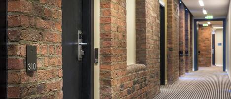 A corridor with brick walls, a door labeled "310", and a patterned carpet.