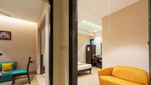 A hotel room with a bed, a sofa, a chair, and a desk. - Cosy Grand @Chanakyapuri by The Cosy Hotels (New Delhi)