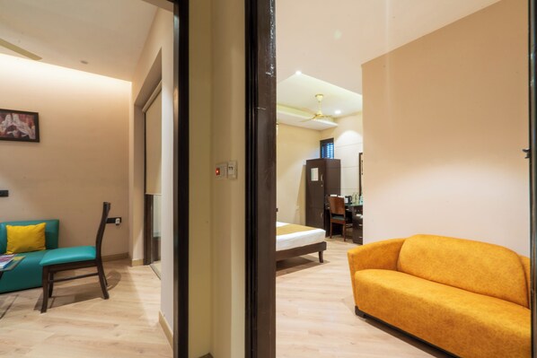 A hotel room with a bed, a sofa, a chair, and a desk. - Cosy Grand @Chanakyapuri by The Cosy Hotels (New Delhi)