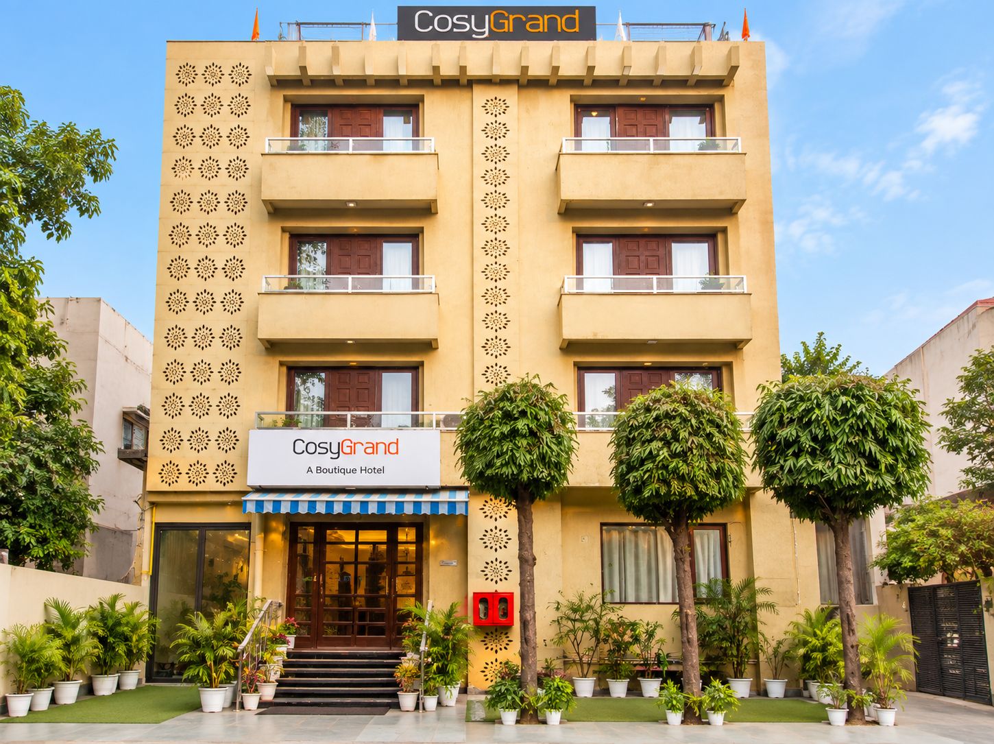 A hotel with a sign reading 'CosyGrand A Boutique Hotel' and a symmetrical facade with balconies.