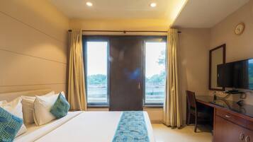Una habitación de hotel con una cama, un escritorio, un televisor y una ventana con cortinas.