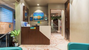 A reception area with a wooden reception desk, a poster of India, and a staircase leading to an upper floor. - Cosy Grand @Chanakyapuri by The Cosy Hotels (New Delhi)