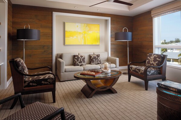 A modern living room with a sofa, two armchairs, a glass coffee table with chess pieces, and a large abstract painting. - The Residences at Siesta Key Beach by Hyatt Vacation Club (Siesta Key)