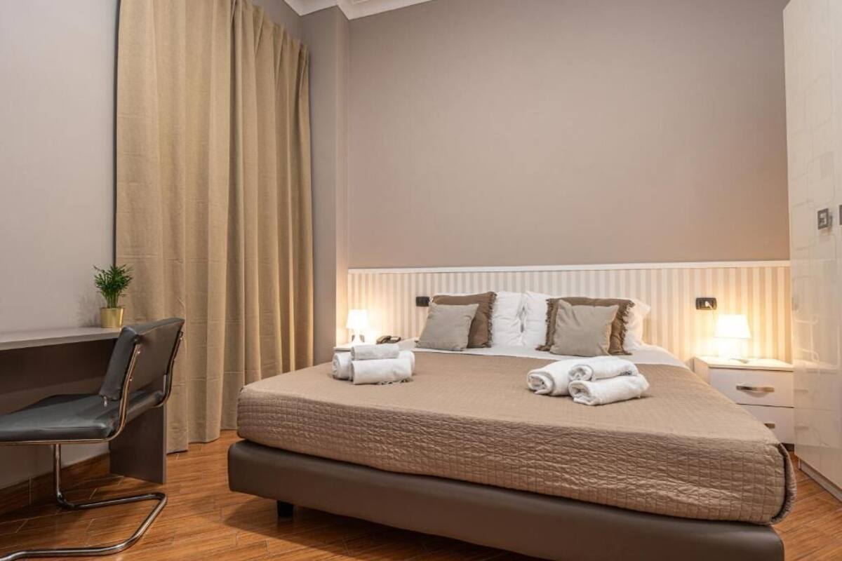 A hotel room with a large bed, a desk, and a chair.