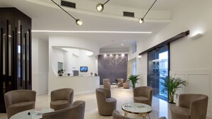 A modern lobby with a reception desk, seating area, and a large window.