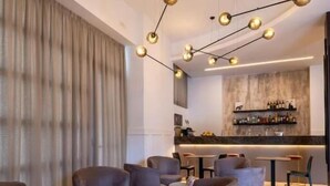 A modern lounge area with round seating, a bar with a marble countertop, and pendant lighting.
