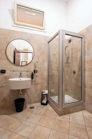 Un baño con lavamanos, espejo y ducha.