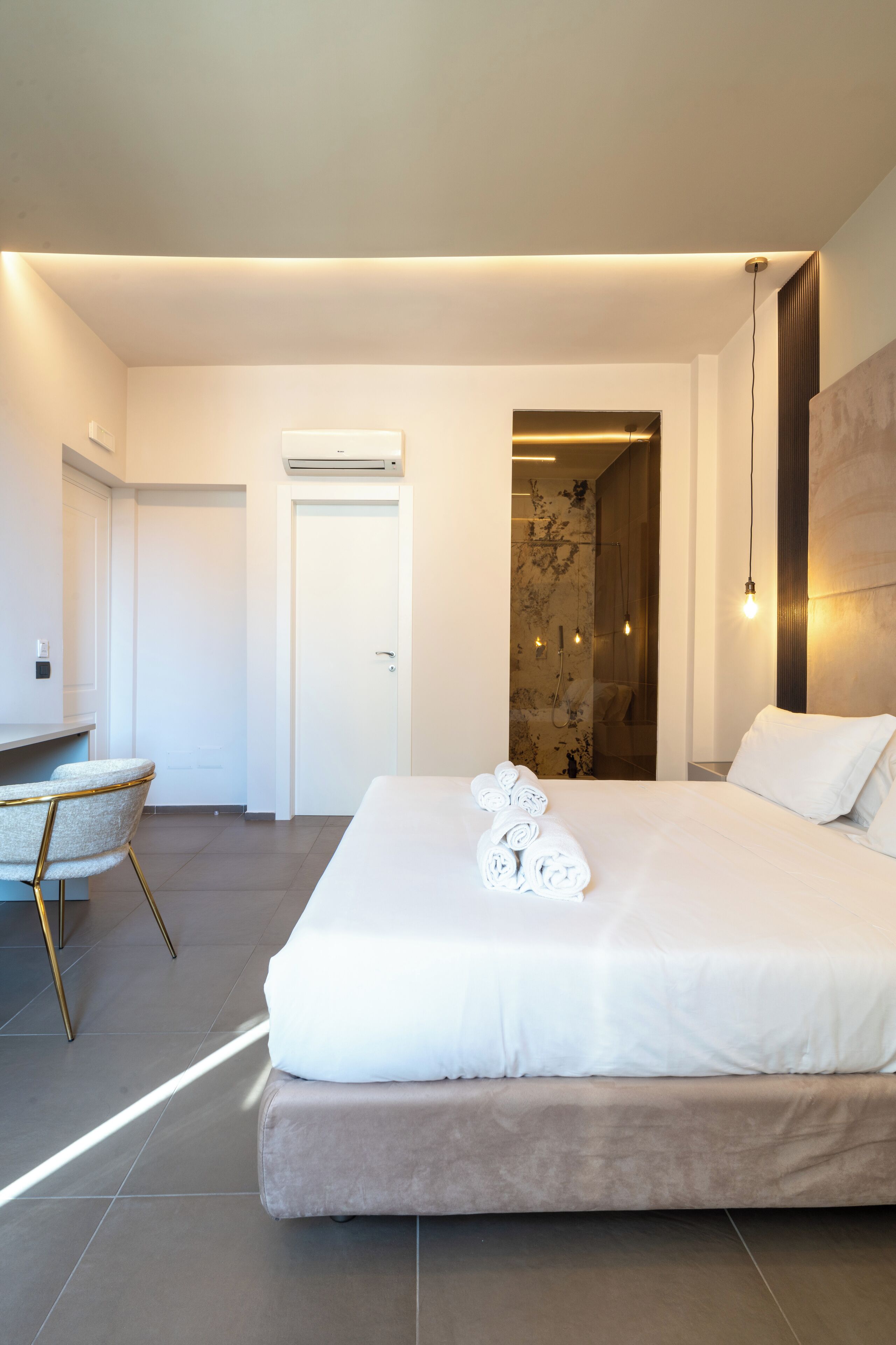 A modern hotel room with a large bed, a desk, and a shower area.