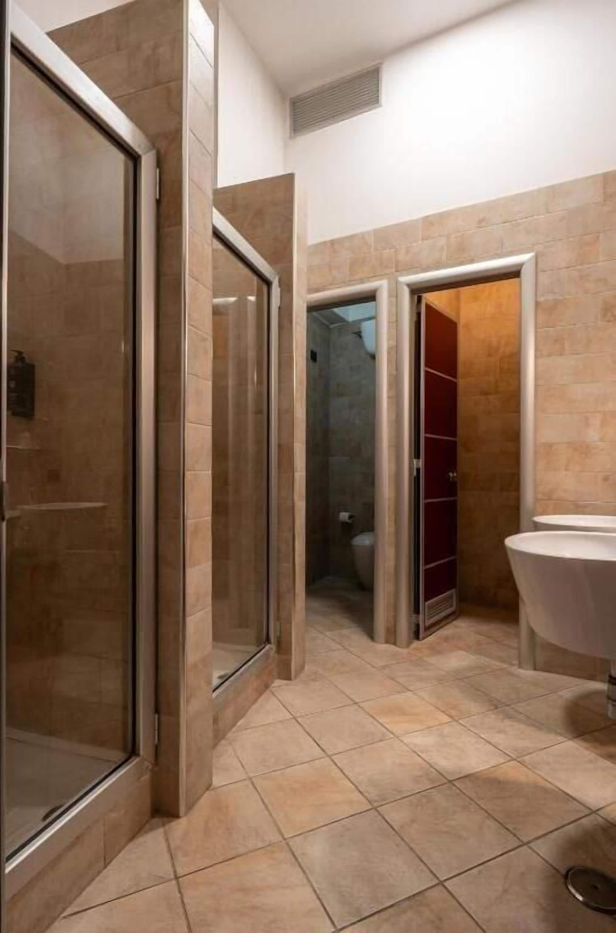 A modern bathroom with a glass shower enclosure, a white sink, and a red cabinet.