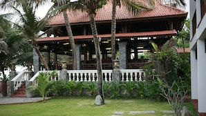 A traditional building with a tiled roof, a stone pathway, and lush greenery. - Novela Muine Resort & Spa (Mui Ne)