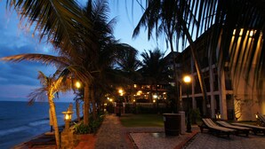A beachfront resort with a pathway leading to a pool area, palm trees, and lounge chairs. - Novela Muine Resort & Spa (Mui Ne)