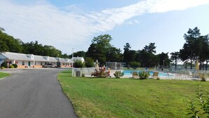 Um motel com piscina, área de piquenique coberta e estrada de acesso.