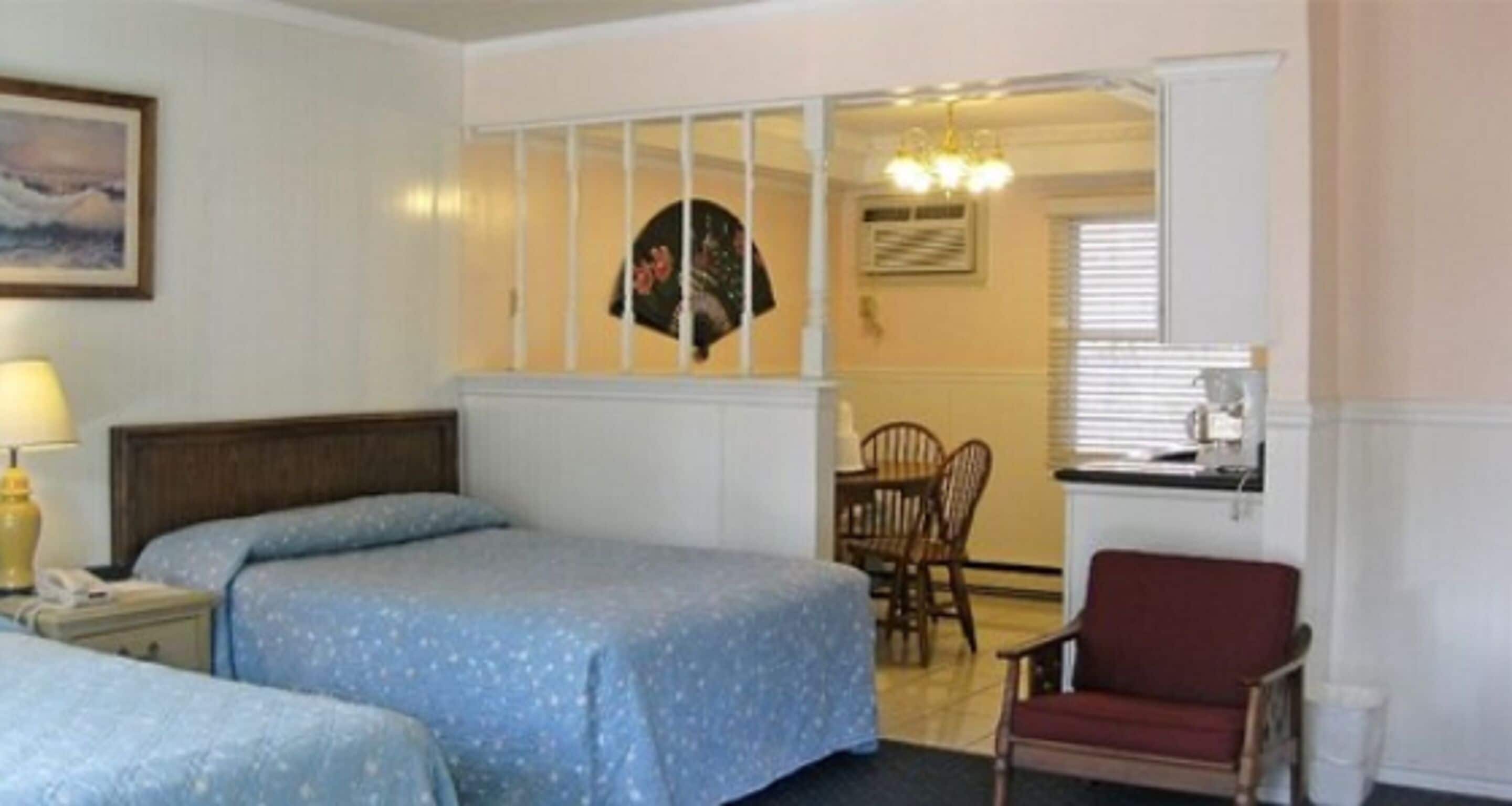 A hotel room with a bed, a chair, a desk, and a dining table.