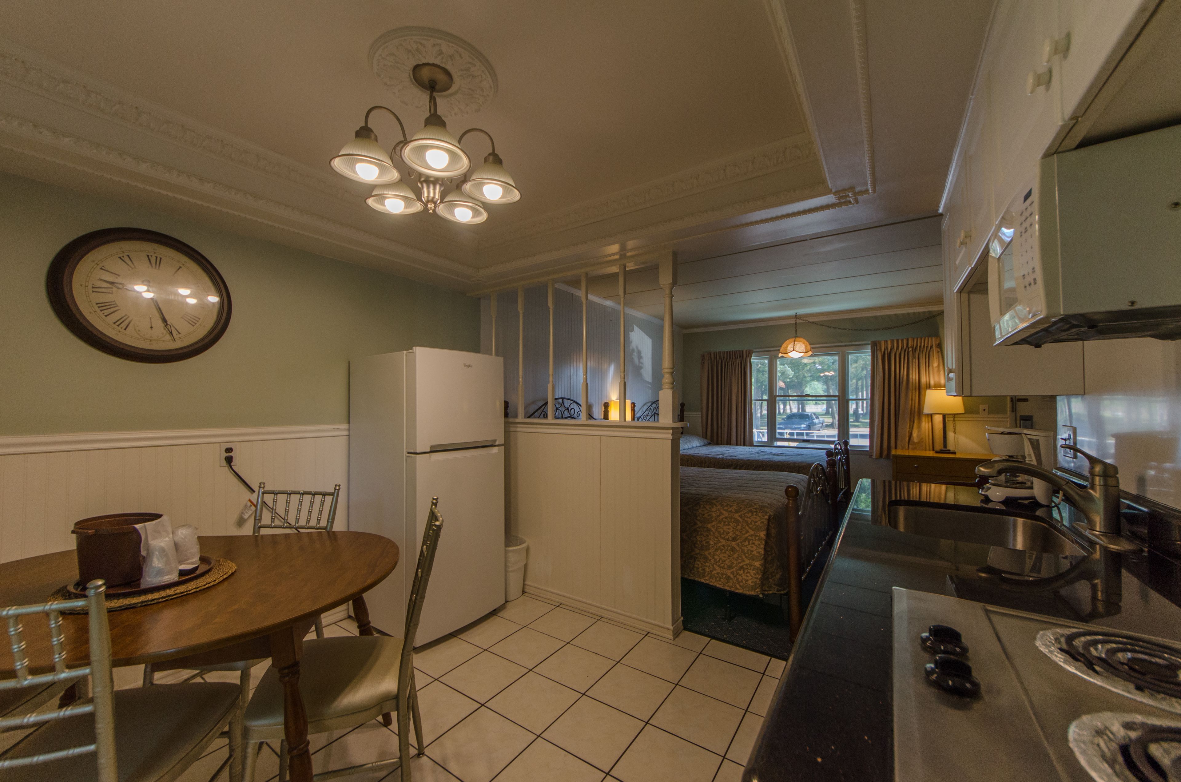 Una cocina compacta con comedor, refrigerador, estufa y un reloj en la pared.