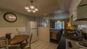 Una cocina compacta con comedor, refrigerador, estufa y un reloj en la pared.