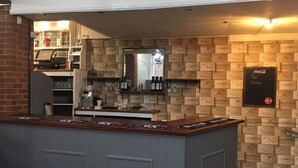 A bar area with a counter, shelves with bottles, and a wall decorated with vintage-style boxes. - The Old Castle (Weymouth)
