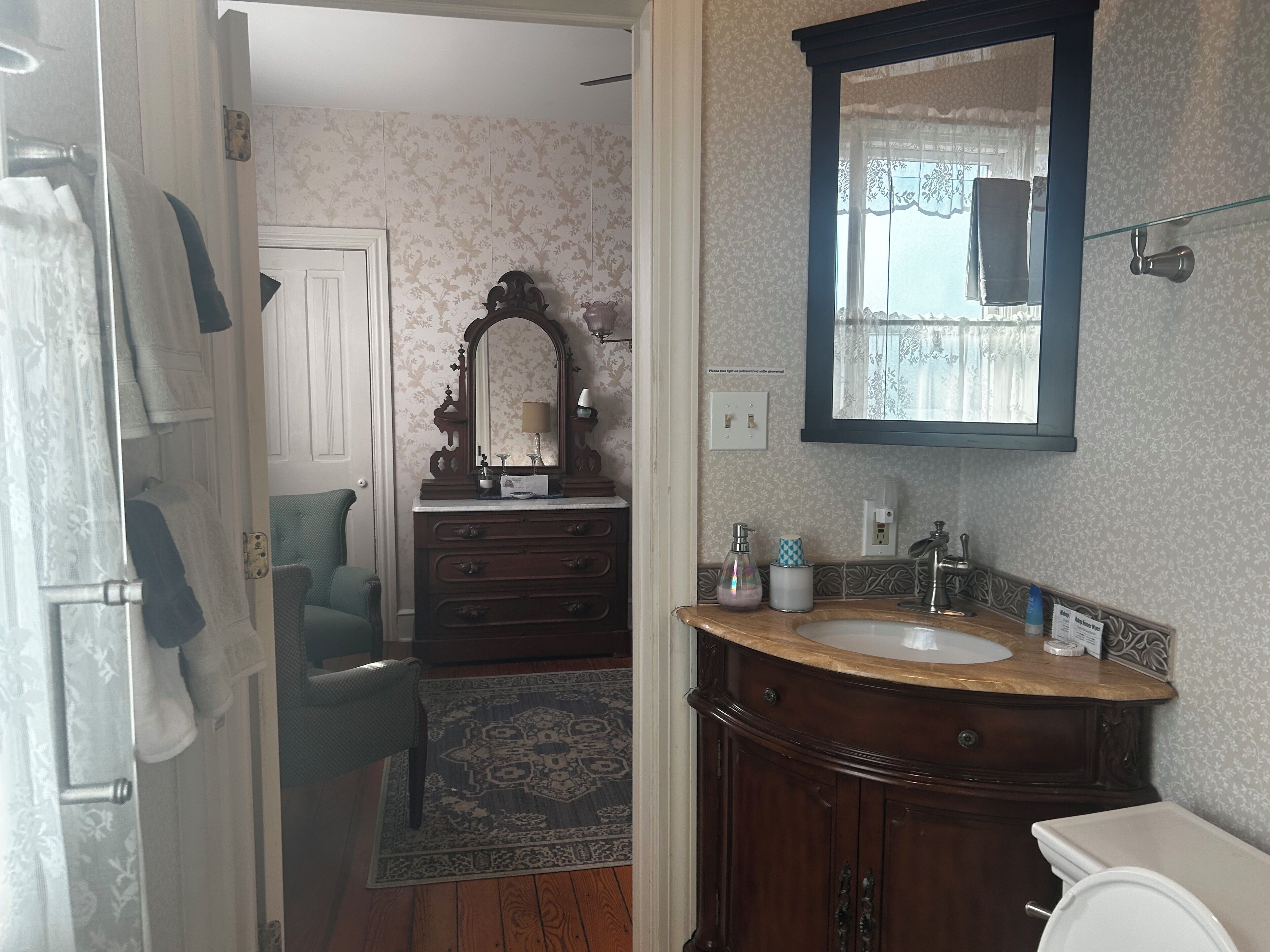 A bathroom with a wooden vanity, a large mirror, a sink, and a toilet.