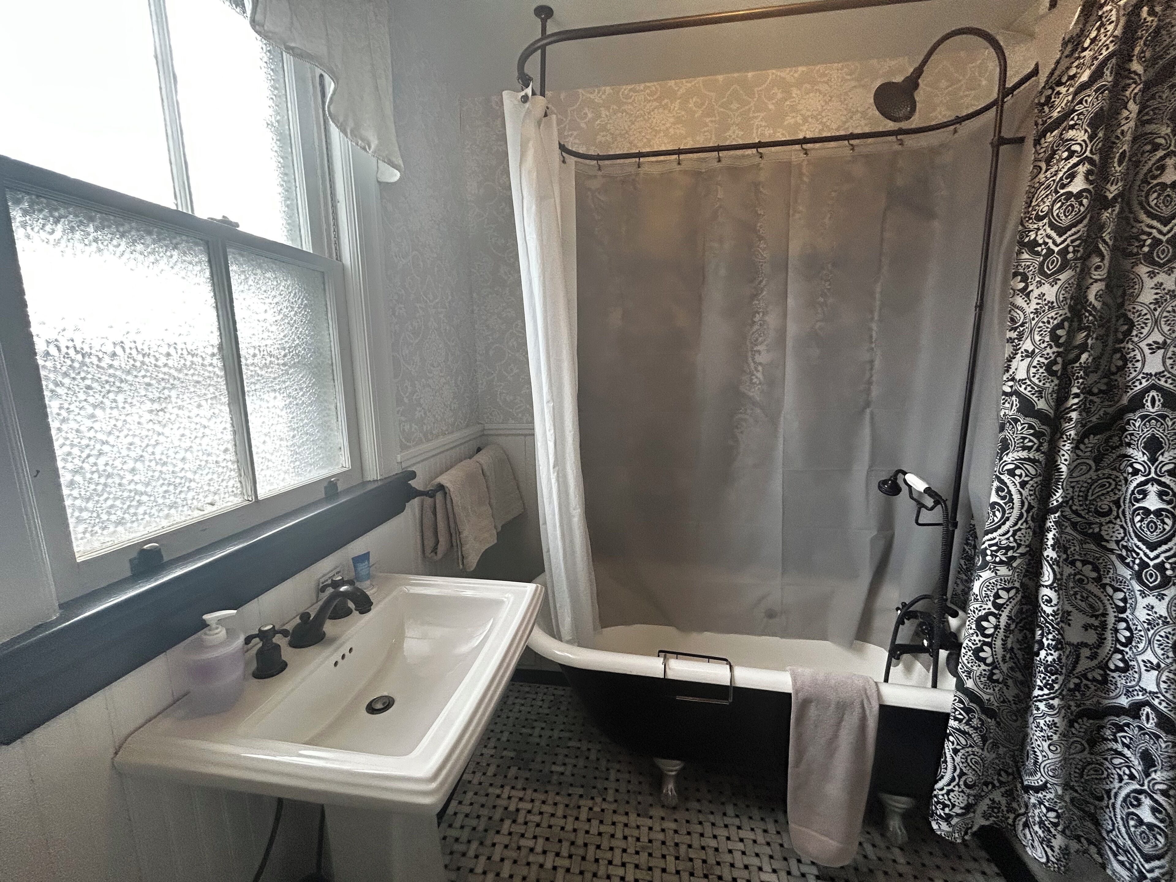 A bathroom with a white sink, a bathtub, and a shower curtain.