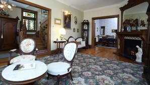 Un salón tradicional con chimenea, muebles de madera y una escalera.