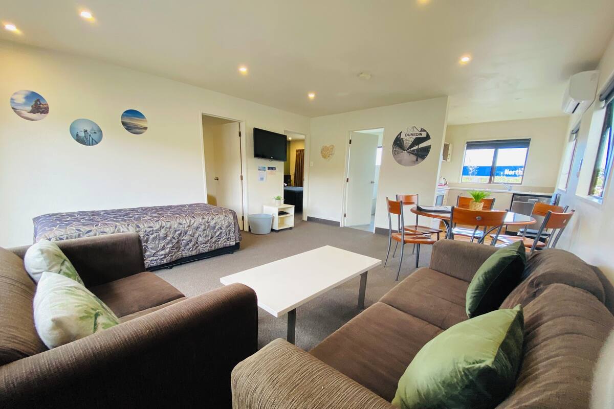 A modern living room with a sofa, a coffee table, and a dining area with chairs and a table.