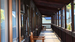 A covered outdoor area with wooden benches and large windows. - Commodore Motels (Dunedin)